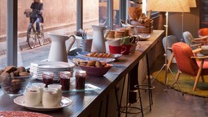 A breakfast bar with various food items and utensils, a bicycle outside the window, and a lamp on the right.
