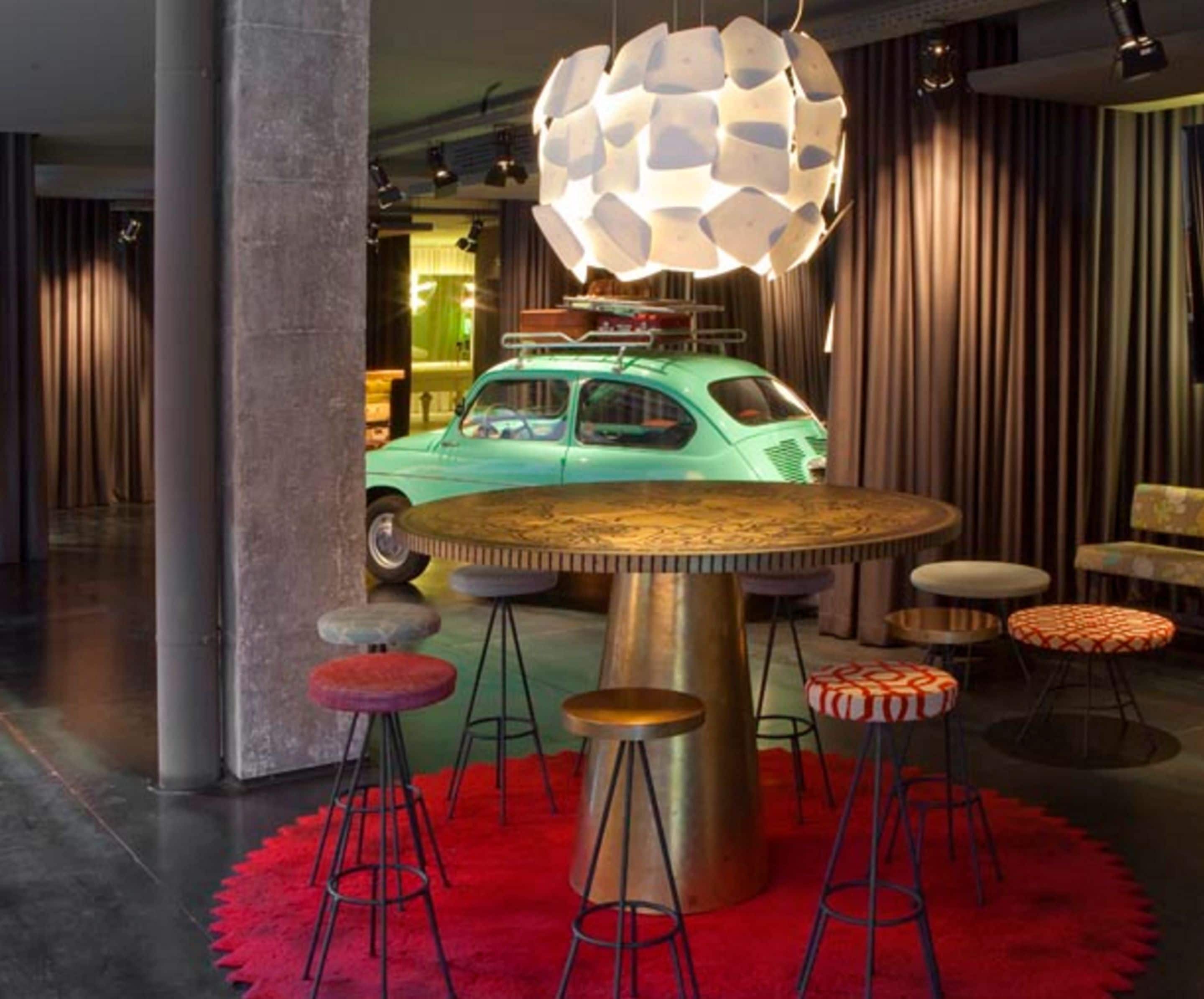 A retro-themed bar area with a green car model, round tables, and stools.