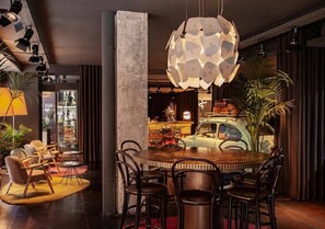 Un espace de salle à manger moderne avec une table ronde en bois, des chaises foncées et un luminaire suspendu au design géométrique original.