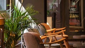 A modern lounge area with a large floor lamp, a comfortable armchair, and a potted plant. - Sixties Ramblas (Barcelona)