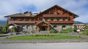 A large wooden hotel with multiple balconies, a stone facade, and a well-maintained garden.