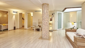 A modern hotel lobby with a central mosaic pillar, a reception desk, and a seating area.