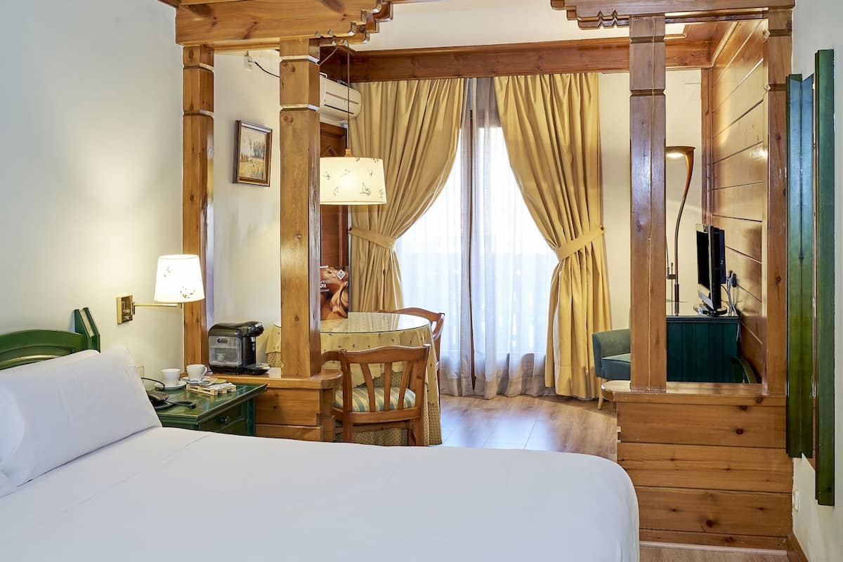 Ein Hotelzimmer mit Bett, Schreibtisch mit Lampe, Stuhl und Fernseher.