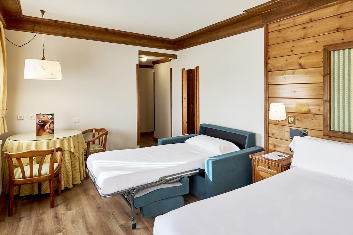 Ein Zimmer mit zwei Betten, einem Schreibtisch mit Stuhl, einer Lampe und einer Wandverkleidung aus Holz.