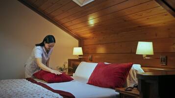 A wooden-paneled room with a bed, two bedside lamps, and a nightstand.