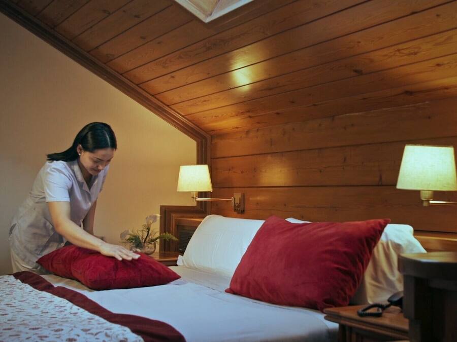 A wooden-paneled room with a bed, two bedside lamps, and a nightstand.