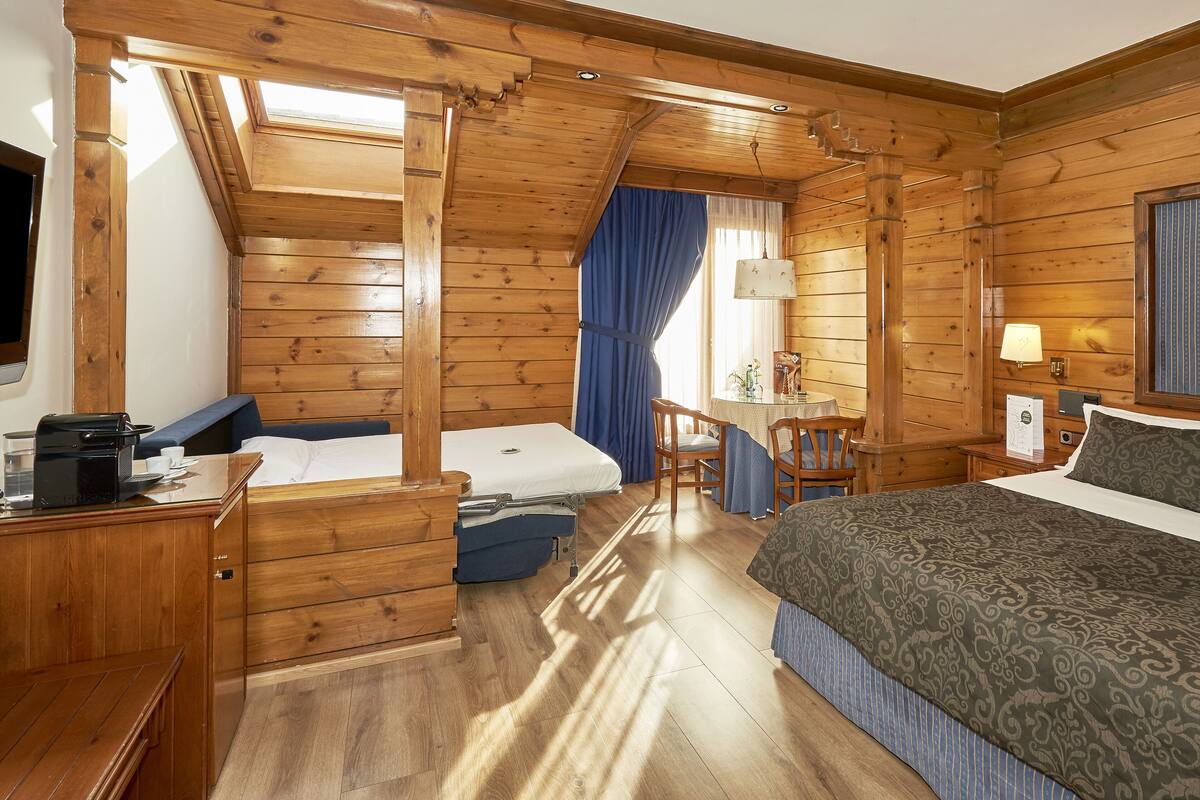 Ein Zimmer mit Holzboden, einem Bett, einem Schreibtisch, einem Sessel und einem Tisch.