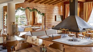 A cozy wooden interior with a fireplace, seating areas, and a dining table.