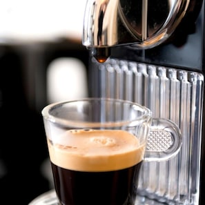 A coffee machine dispensing coffee into a clear glass cup. - Choiseul Opera (Paris)