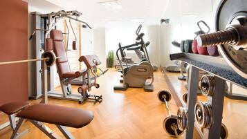 Un gimnasio con diverso equipo de ejercicio, incluyendo bancos, máquinas de pesas y máquinas de cardio.