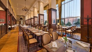 Un comedor amplio con mesas largas, sillas y candelabros.