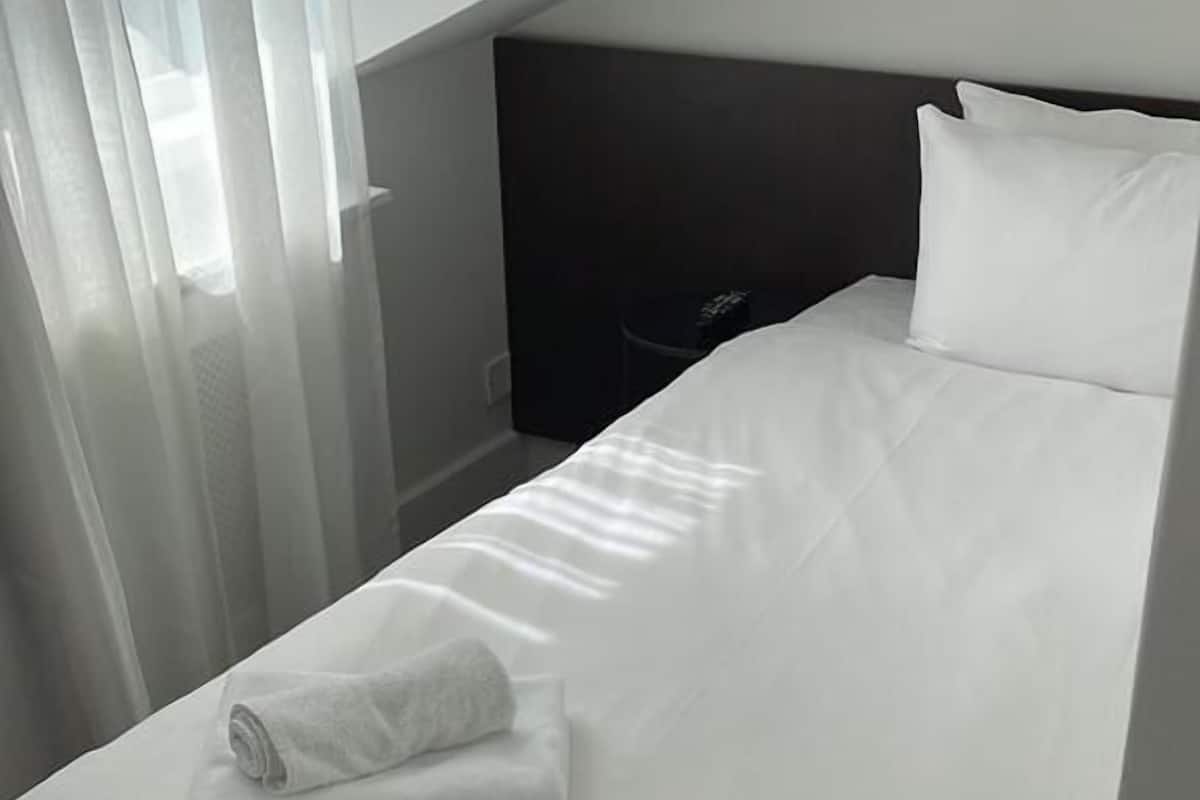 Eenpersoonskamer, en-suite badkamer | Een kluis op de kamer, een bureau, een strijkplank/strijkijzer