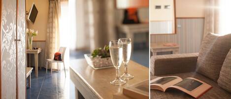 A hotel room with a wooden table, two champagne flutes, a book, and a sofa.
