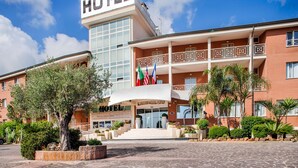 Un hôtel reconnaissable à son grand panneau « HÔTEL », à son entrée centrale avec des marches et à ses nombreux balcons.