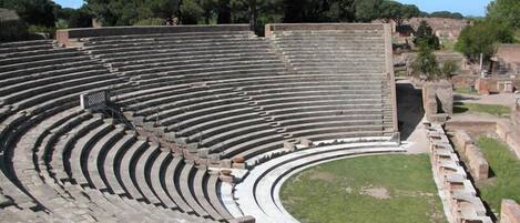 Un antiguo anfiteatro con asientos escalonados y una zona central para el escenario.