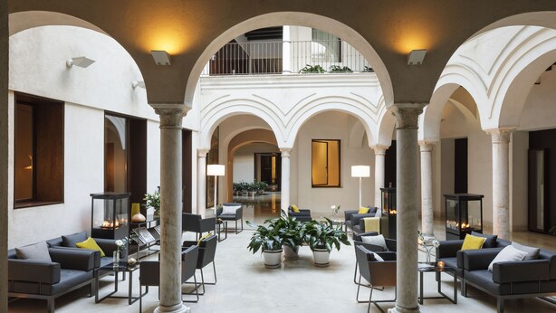A spacious indoor area with a central open space surrounded by seating arrangements and columns. - Hotel Posada del Lucero (Seville)