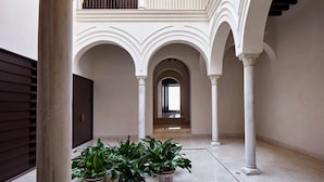An interior courtyard with arches, columns, and potted plants. - Hotel Posada del Lucero (Seville)