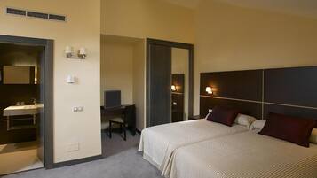 A hotel room with a bed, a desk, a chair, a mirror, and a bathroom with a sink.