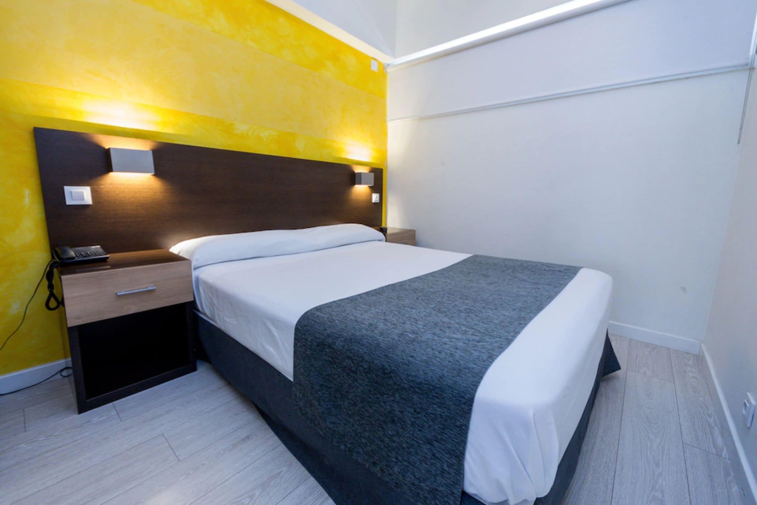 Ein modernes Hotelzimmer mit einem Bett, Nachttischen und einem Beistelltisch.