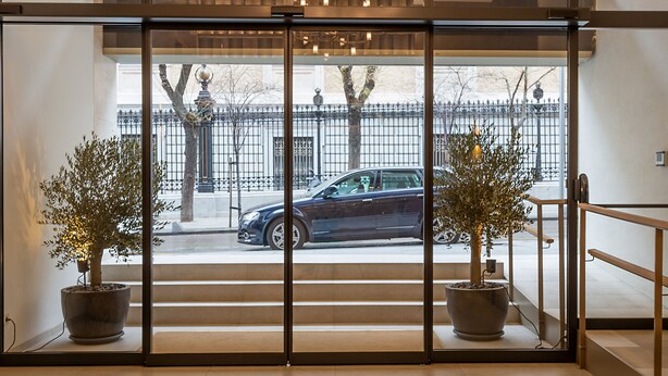 A modern interior with a geometric chandelier, large windows, and potted plants. - Apartamentos Recoletos (Madrid)