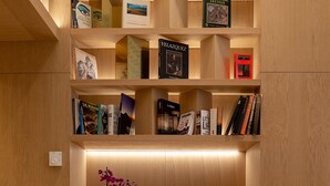 A modern library with wooden shelves, books, and a potted orchid. - Apartamentos Recoletos (Madrid)