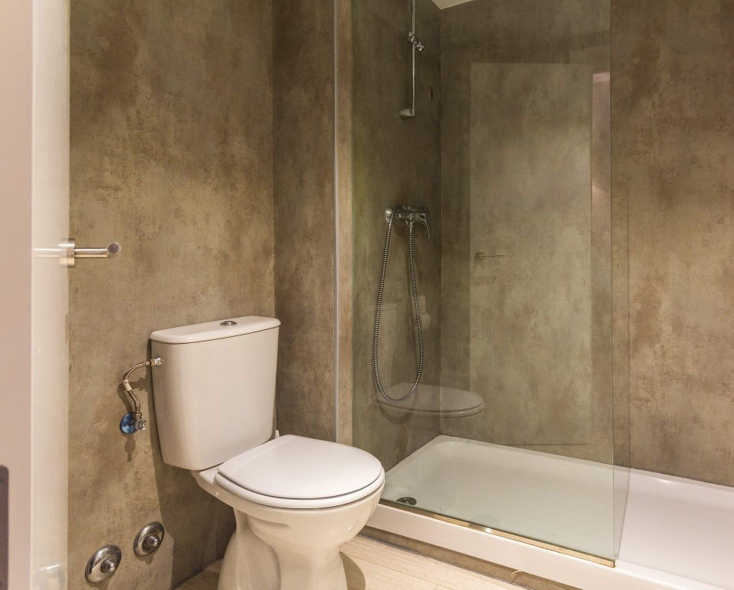 Une salle de bain moderne équipée de toilettes, d’une douche à parois de verre et d’une baignoire.