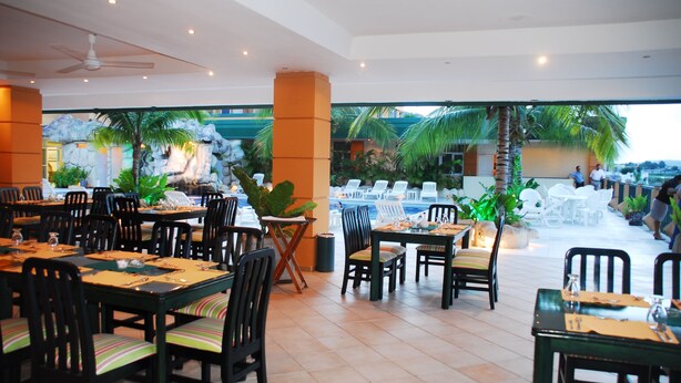 Un restaurant doté d’une terrasse, de tables avec des chaises et offrant une vue sur l’océan.