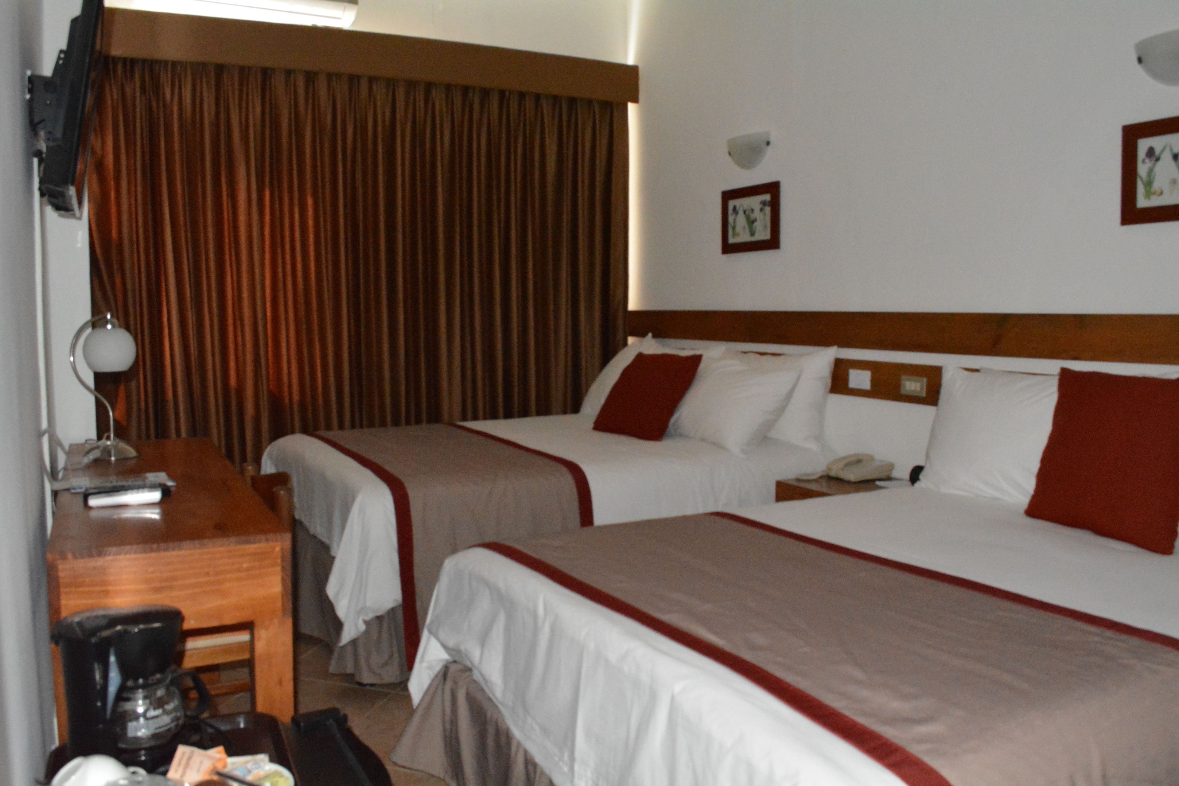 A hotel room with two beds, a desk, a coffee maker, and a telephone.