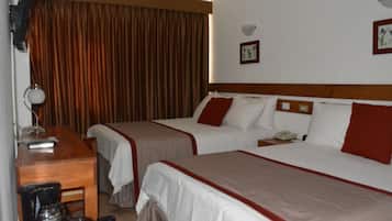 A hotel room with two beds, a desk, a coffee maker, and a telephone.