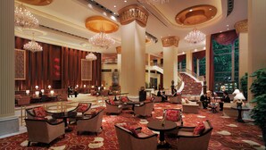 A spacious lobby with high ceilings, ornate chandeliers, and a grand staircase.
