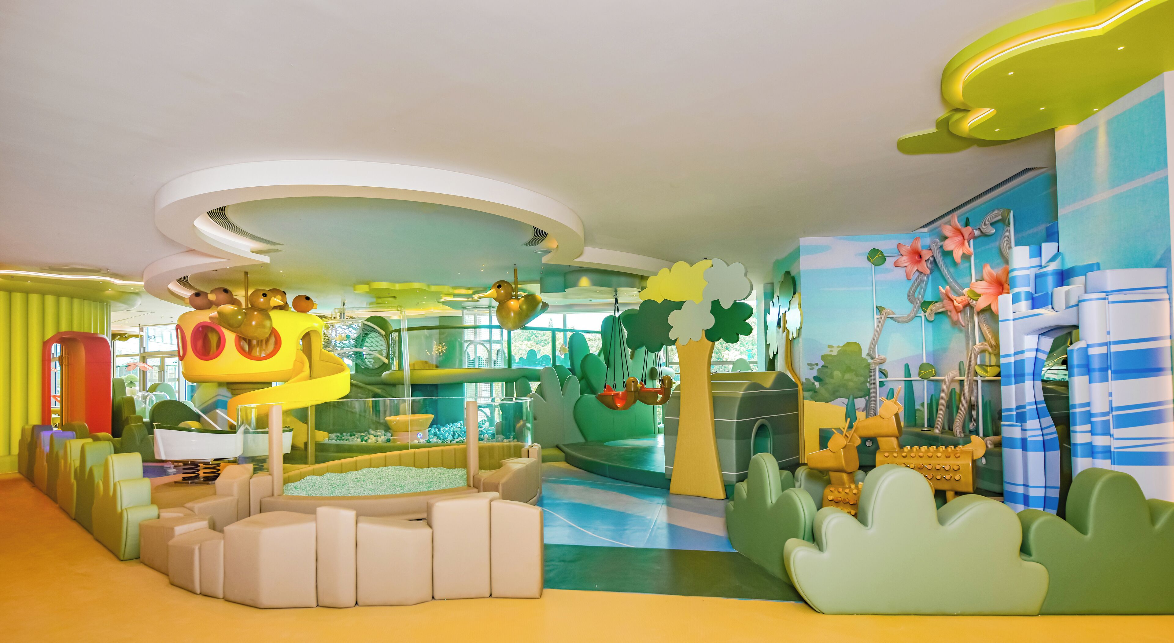 A children's play area with soft seating, a slide, and colorful decorations.