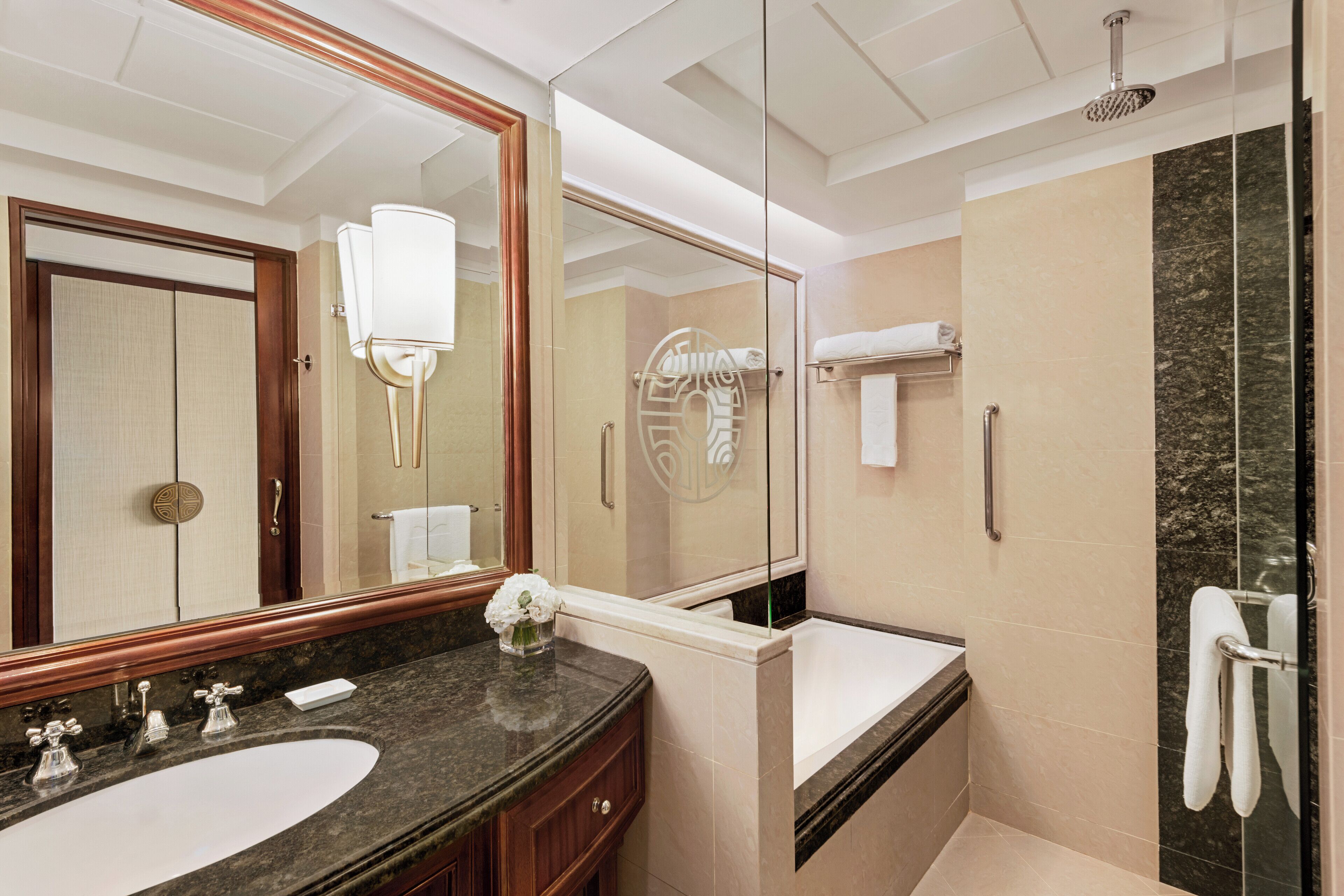 Un baño moderno con un espejo grande, un lavabo, una bañera y una zona de ducha.