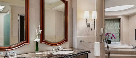 A modern bathroom with two sinks, large mirrors, and a bathtub.