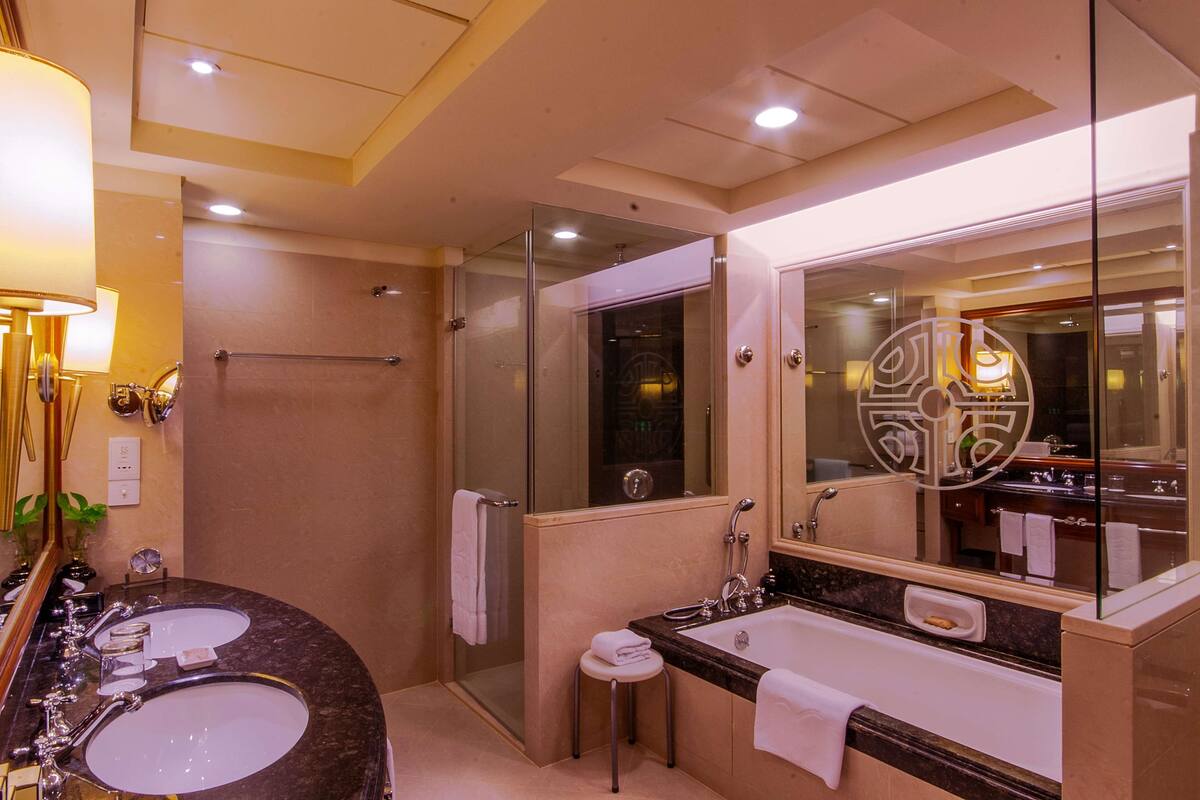 A modern bathroom with a glass-enclosed shower, a double sink vanity, and a large mirror with a decorative frame.