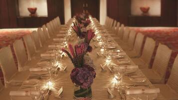 A long dining table set for a formal event with floral centerpieces, candles, and neatly arranged tableware.