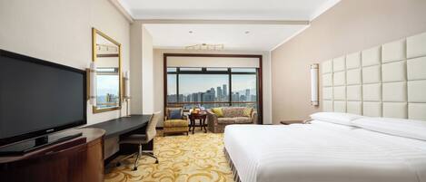 Habitación de hotel con una cama grande, televisión, escritorio y vistas a la ciudad.