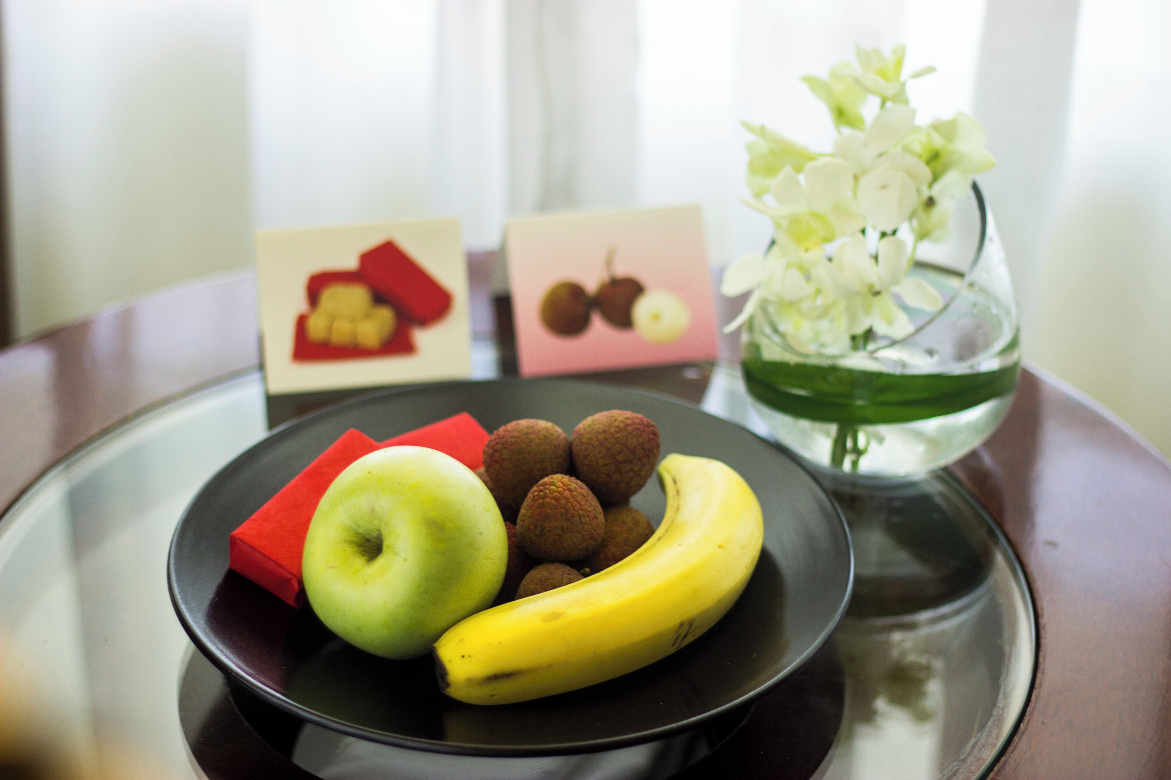 A plate with an apple, lychees, and a banana on a tray.