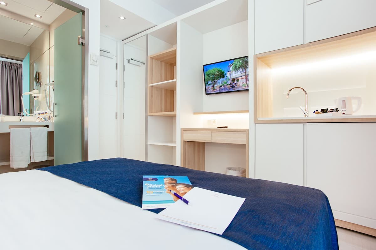 A hotel room with a bed, a desk, a TV, and a bathroom.