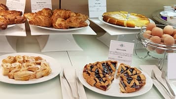 A buffet counter with various food items including pastries, a pie, and a bowl of eggs.