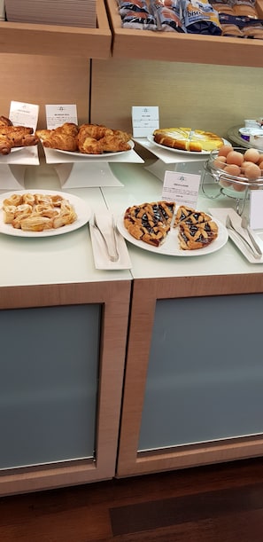 A buffet counter with various food items including pastries, a pie, and a bowl of eggs. - Best Western Hotel San Marco (Siena)