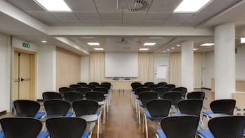 Ein Konferenzraum mit Reihen von Stühlen, einem Projektor, einer Tafel und einem Rednerpult.