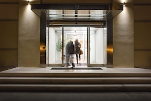 A hotel entrance with a glass door, a metal frame, and a light fixture above.