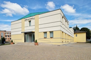 A building with a sign reading 'HOTEL SAN CARLO.' It features a flat roof, a large entrance with glass doors, and a paved courtyard. - Best Western Hotel San Marco (Siena)