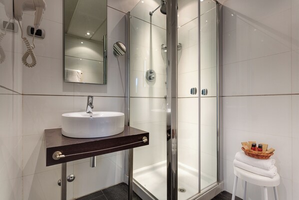 A modern bathroom with a glass-enclosed shower, a white sink, and a hairdryer mounted on the wall. - Best Western Hotel San Marco (Siena)