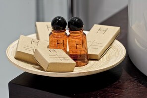A wooden tray with two amber-colored bottles and three cardboard boxes on a dark surface. - Best Western Hotel San Marco (Siena)