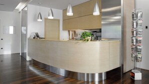 Een moderne receptie met een gebogen balie, hangende verlichting, een plant en een tijdschriftenrek.