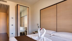 Een hotelkamer met een bed, een houten hoofdeinde, een spiegel en een deur.