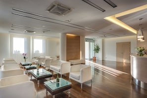 A modern waiting area with white chairs, glass tables, and a reception desk. - Best Western Hotel San Marco (Siena)