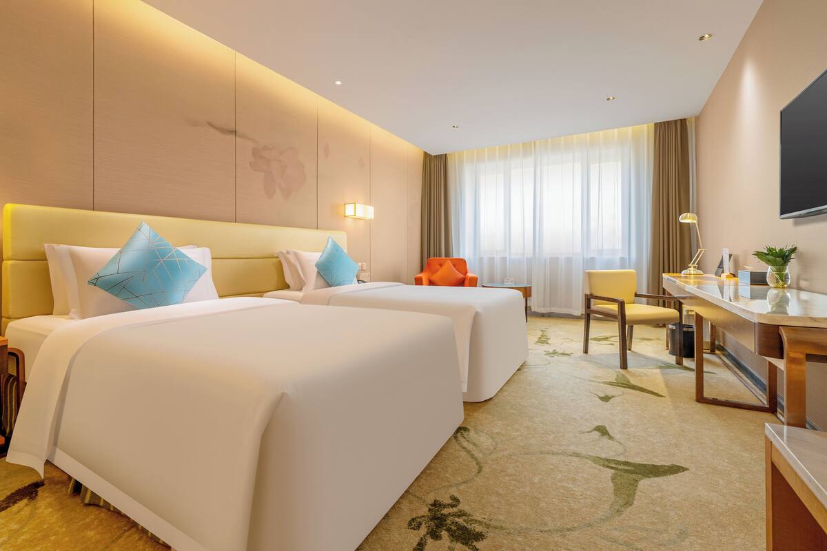 Een hotelkamer met twee bedden, een bureau, een stoel en een televisie.
