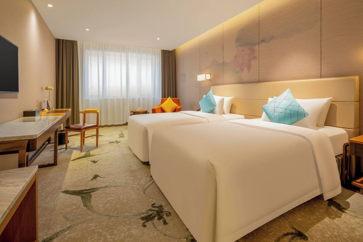 Een hotelkamer met twee bedden, een bureau, een stoel en een televisie.